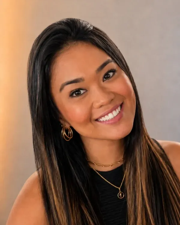Laura Assano, sorrindo, com cabelo longo e blusa preta.